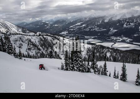 Vue de dessus d'un snowboarder anonyme descendant sur une majestueuse pente de montagne enneigée contre un ciel nuageux clair tout en profitant de vacances d'hiver au Canada Banque D'Images