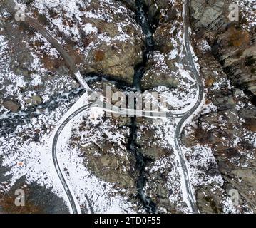 Une prise de vue aérienne capture une route de montagne sinueuse recouverte de neige précoce sur le terrain accidenté de la Suisse en automne Banque D'Images