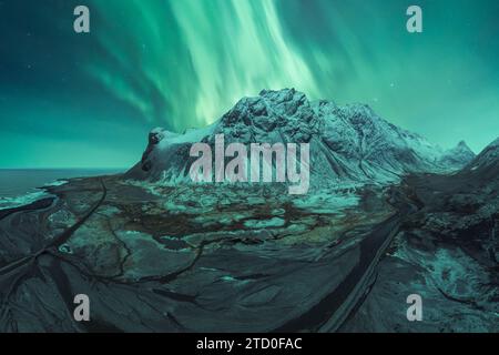 L'époustouflante aurora borealis danse au-dessus d'une montagne enneigée en Islande, offrant un spectacle des merveilles de la nature sous un ciel étoilé. Banque D'Images