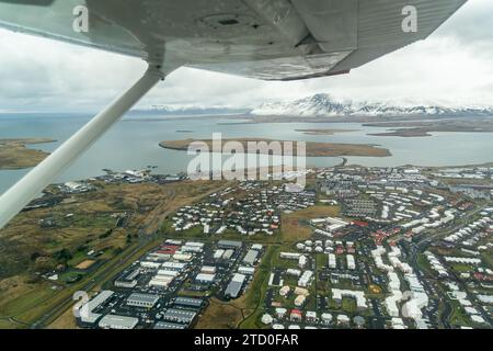 Cette image capture une vue aérienne à couper le souffle de Reykjavik, en Islande, mettant en valeur son paysage urbain sur fond de montagnes spectaculaires et de coas Banque D'Images