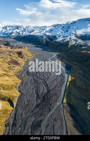 Superbe prise de vue aérienne d'une rivière sinueuse serpentant à travers un paysage islandais spectaculaire avec des montagnes enneigées au loin. Banque D'Images