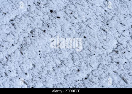 Photo en gros plan d'une surface de glace texturée tachetée de débris incrustés et de motifs subtils. Banque D'Images