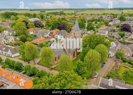 Vue aérienne de la belle église historique au milieu des maisons et des arbres verts contre un paysage luxuriant à la campagne rurale Banque D'Images