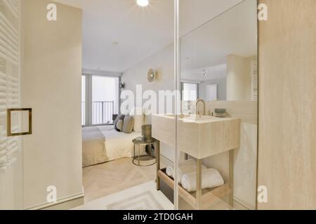 Lavabo avec miroir par mur de verre à côté du lit dans la chambre dans un spacieux appartement de luxe contemporain Banque D'Images