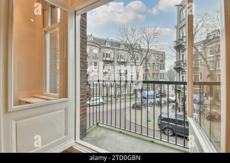 Immeubles d'appartements et voitures garés dans la rue contre le ciel bleu vu à travers la grande fenêtre ouverte à la maison contemporaine Banque D'Images