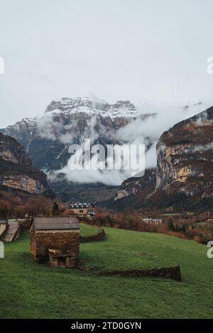 Vue majestueuse sur les montagnes enneigées des Pyrénées entourées de brume, avec le village pittoresque de Torla au premier plan, mettant en valeur le beaut naturel Banque D'Images