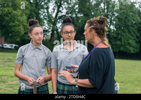 Un groupe de filles dans un lycée britannique se tient à l'extérieur pour parler à un enseignant et mentor. Banque D'Images