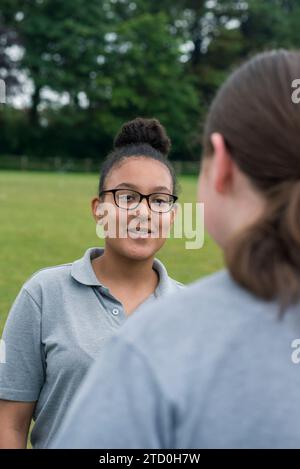 Un groupe de filles dans un lycée britannique se tient à l'extérieur pour parler à un enseignant et mentor. Banque D'Images