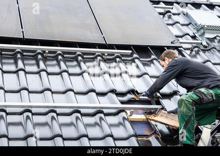 Technicien travaillant sur la structure de montage des panneaux solaires sur le toit d'une maison Banque D'Images