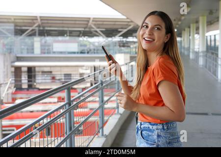 Jolie jeune femme brésilienne utilisant son téléphone portable marchant dans la gare de Sao Paulo métropole, Brésil Banque D'Images