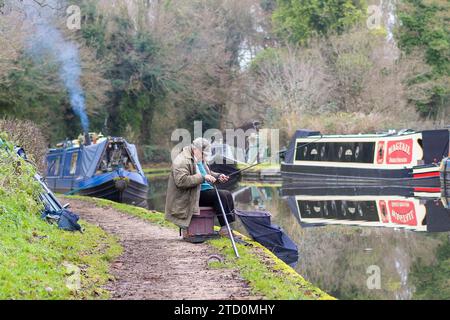 Stourbridge, Royaume-Uni. 15 décembre 2023. Météo britannique : c'est une matinée fraîche et ennuyeuse dans les Midlands, mais cela n'empêche pas les gens de sortir et de profiter de leur passe-temps préféré. Ce monsieur installe son équipement de pêche pour une matinée tranquille de pêche sur le canal, loin de l'agitation de la ville de Noël shopping. Crédit : Lee Hudson/Alamy Live News Banque D'Images