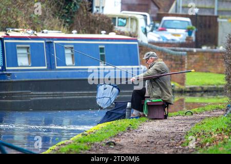 Stourbridge, Royaume-Uni. 15 décembre 2023. Météo britannique : c'est une matinée fraîche et ennuyeuse dans les Midlands, mais cela n'empêche pas les gens de sortir et de profiter de leur passe-temps préféré. Ce monsieur pêche un poisson, pêché sur le canal, lors d'une matinée tranquille de pêche, loin de l'agitation de la ville de Noël shopping. Crédit : Lee Hudson/Alamy Live News Banque D'Images