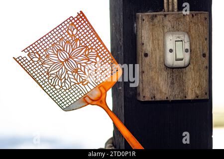 Une vieille tapette à mouches attachée à un faisceau avec un interrupteur de lumière dans la cour Banque D'Images