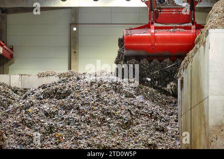 Décharge de combustible dérivé des déchets . Manutention et transport du combustible obtenu à partir de déchets (RDF) par grappin rouge à la chaudière pour combustion. Traitement de munic Banque D'Images