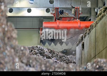 Décharge de combustible dérivé des déchets . Manutention et transport du combustible obtenu à partir de déchets (RDF) par grappin rouge à la chaudière pour combustion. Banque D'Images