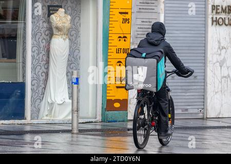 Pilote Deliveroo sur un vélo de poussée effectuant une livraison de nourriture à Cork, en Irlande. Banque D'Images