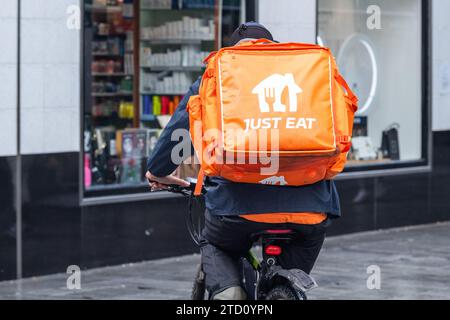 Il suffit de manger coureur sur un vélo de poussée faisant une livraison de nourriture à Cork, Irlande. Banque D'Images