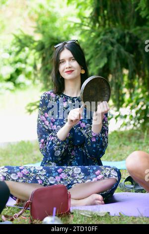 Jeune femme jouant au gong, cloche du temple tibétain, pour méditer. 12 juillet 2020. Kiev Ukraine Banque D'Images