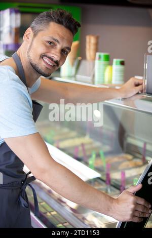 joyeux vendeur de crème glacée souriant à la caméra Banque D'Images