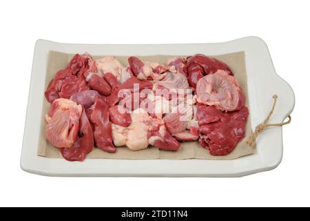 Abats de poulet sur une planche en céramique isolé sur fond blanc. Les estomacs de poulet, les coeurs et les foies sont préparés pour la cuisson. Viande crue. Banque D'Images