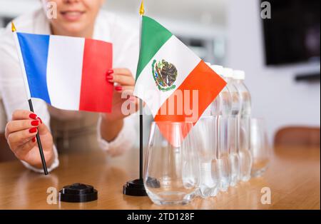 Fille méconnaissable pose des drapeaux midget du Mexique et de la France avant les négociations internationales Banque D'Images