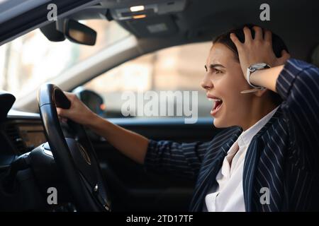 Une conductrice en colère criant dans sa voiture. Coincé dans un embouteillage Banque D'Images