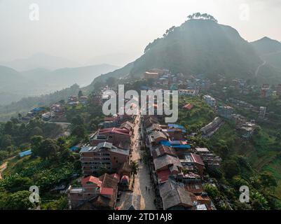 Vue aérienne rétroéclairée avec des godsrays et de la brume entourant la ville népalaise de Bandipur. Rue principale avec commerces et activités commerciales. Népal Banque D'Images