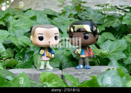 Figurines Funko Pop d'Eleven et Lucas de la série télévisée surnaturelle Netflix Stranger Things. Feuilles de lierre verte, jardin abandonné, amis. Banque D'Images