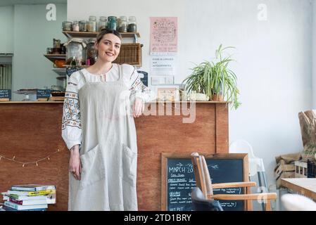 Une femme se tient dans le petit café / restaurant local qu'elle dirige qui sert de la bonne nourriture et des boissons Banque D'Images