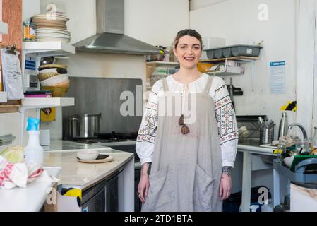 Une femme se tient dans le petit café / restaurant local qu'elle dirige qui sert de la bonne nourriture et des boissons Banque D'Images