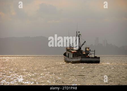 Vieux bateau de pêche naviguant sur la côte de la ville de Santos en fin d'après-midi. Banque D'Images