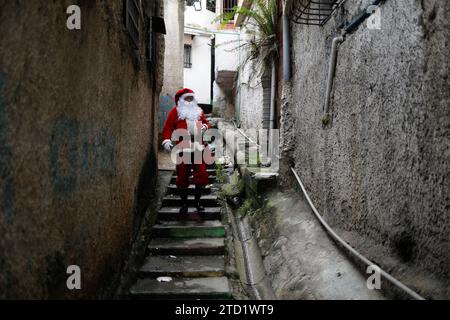 Caracas, Venezuela. 15 décembre 2023. 15 décembre 2023, Venezuela, Caracas : un homme habillé en Père Noël marche dans une ruelle dans le quartier pauvre de Petare lors de la remise de la campagne cadeau «Un jouet, un bon message». Photo : Pedro Mattey/dpa crédit : dpa Picture alliance/Alamy Live News Banque D'Images