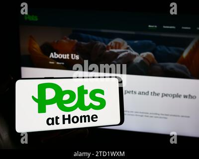 Personne tenant un smartphone avec le logo de la société britannique de vente au détail de fournitures Pets at Home Group devant le site Web. Concentrez-vous sur l'affichage du téléphone. Banque D'Images