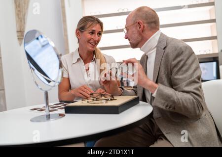 Opticien et client souriant et ajustant la sélection de lunettes dans le magasin d'optique Banque D'Images