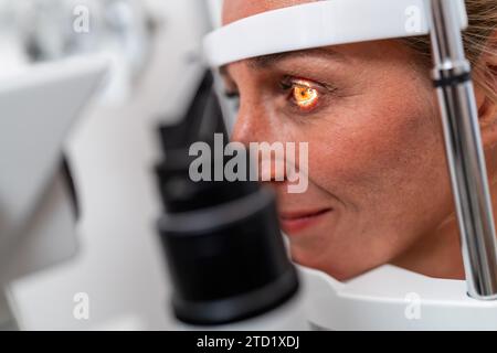Femme subissant un examen de la vue avec un focus sur son œil éclairé à l'aide d'une lampe à fente à la clinique. Gros plan. Soins de santé et médecine conce Banque D'Images