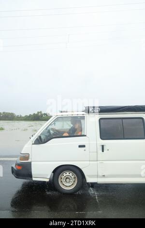 Car tente de passer une route dans la banlieue nord de Holloways Beach à Cairns à la suite du cyclone tropical Jasper. Le cyclone tropical Jasper a touché terre sur la région de Cairns en tant que système de catégorie 2 le mercredi 13 décembre, apportant des inondations généralisées, des débris et des vents puissants. Beaucoup dans l'extrême nord du Queensland connaissent les tempêtes tropicales, mais les variations de terrain et les conditions terrestres et côtières continuent d'apporter de nouveaux problèmes tels que les inondations soudaines et l'érosion. Certaines zones comme les banlieues des plages du Nord peuvent être inondées, comme c'est le cas à Holloways Beach. Banque D'Images