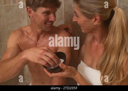 Gros plan d'un couple dans un bain de vapeur partageant un gommage au sel et souriant l'un à l'autre. Image concept d'hôtel spa Wellness Banque D'Images