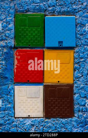 Boîtes de compteurs électriques de différentes couleurs sur un mur bleu dans la ville de Chefchaouen, Maroc Banque D'Images