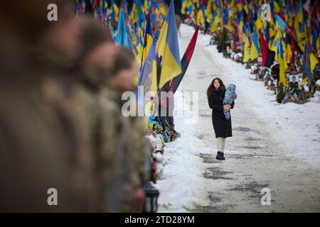 Lviv, Ukraine. 15 décembre 2023. Une mère ukrainienne porte son enfant devant des drapeaux et des banderoles au cimetière militaire de Lychakiv, le 15 décembre 2023 à Lviv, en Ukraine. Crédit : Présidence ukrainienne/Bureau de presse présidentiel ukrainien/Alamy Live News Banque D'Images