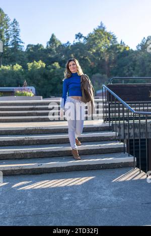 Belle Jeune femme heureuse portant des couleurs vives sur les marches en face de l'hôtel de ville Los Gatos Sunny Afternoon Banque D'Images