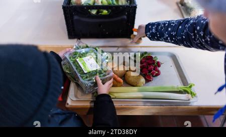 PRODUCTION - 15 décembre 2023, Rhénanie du Nord-Westphalie, Oberhausen : les personnes dans le besoin reçoivent de la nourriture de la banque alimentaire. Files d’attente devant les points de distribution des banques alimentaires, bénévoles à la limite de leurs capacités et demande toujours croissante de nourriture : l’aide à plus de 600 000 personnes dans le besoin en NRW atteint ses limites. Photo : Rolf Vennenbernd/dpa Banque D'Images