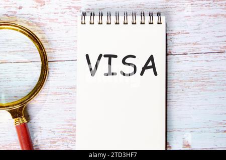 VISA un mot écrit sur un cahier sur des planches de bois à côté d'une loupe Banque D'Images
