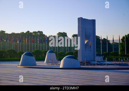 Séoul, Corée du Sud - 2 juin 2023 : une sculpture en béton frappante dans le parc olympique, avec une rangée de drapeaux des nations concurrentes qui flottent dans le backgro Banque D'Images