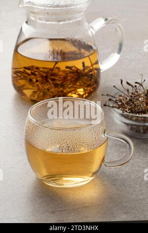 Tasse en verre avec thé à base de tiges de cerises séchées en gros plan Banque D'Images