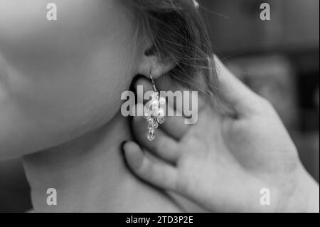 Boucles d'oreilles pour femme. Femme attachant une boucle d'oreille Banque D'Images