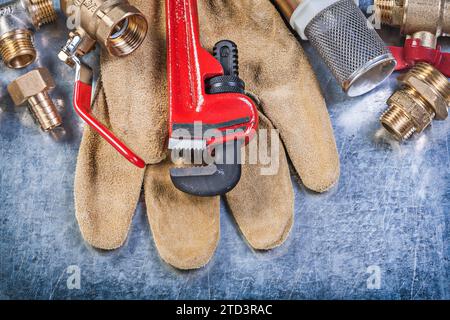 Composition de gants de sécurité en cuir de quincaillerie en laiton de plomberie sur le concept de construction de fond métallique Banque D'Images