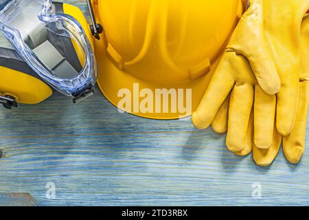 Cache-oreilles lunettes de sécurité gants casque sur concept de construction de planche de bois Banque D'Images