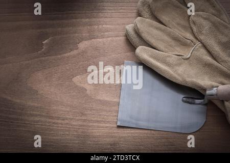 Gants de protection de travail et truelle de plâtrage sur fond en bois vintage Banque D'Images