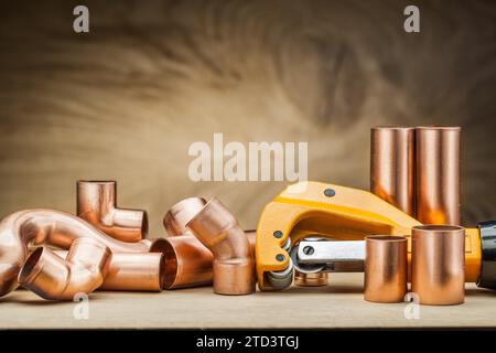 Ensemble de raccords de tuyauterie en cuivre et coupe-tuyau sur fond de bois vintage Banque D'Images
