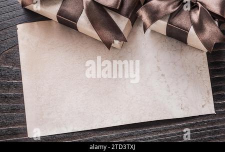 Boîte cadeau avec noeuds bruns, papier sur planche de bois Banque D'Images
